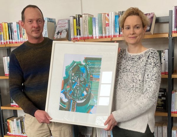 Sonja Hohnholt, Leiterin der Stadtbibliothek Aurich, und Welf-Gerrit Otto, Leiter der Kulturagentur der Ostfriesischen Landschaft, präsentieren das erste Bild der Wechselausstellung (Foto: Stadtbibliothek Aurich)